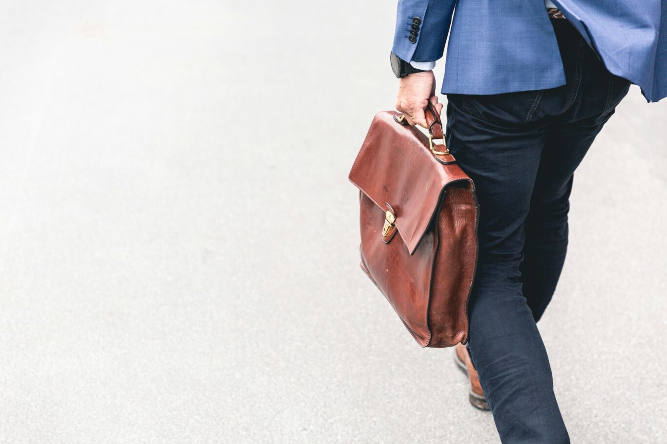 Interim CFO mit brauner Ledertasche auf dem Weg zum Kunden